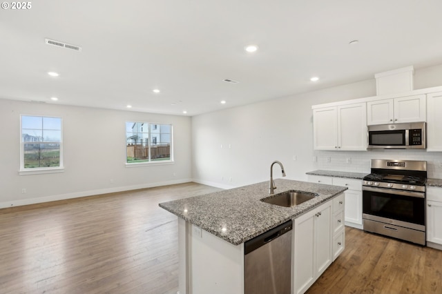 kitchen with appliances with stainless steel finishes, an island with sink, white cabinets, and sink