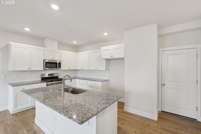 kitchen featuring appliances with stainless steel finishes, white cabinets, a kitchen island with sink, and sink