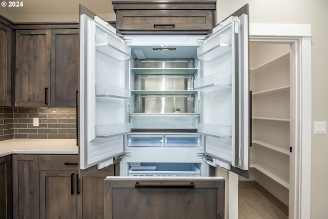 kitchen with backsplash, dark brown cabinetry, hardwood / wood-style floors, and high end fridge