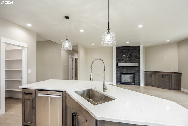 kitchen with dishwasher, sink, hanging light fixtures, an island with sink, and light wood-type flooring