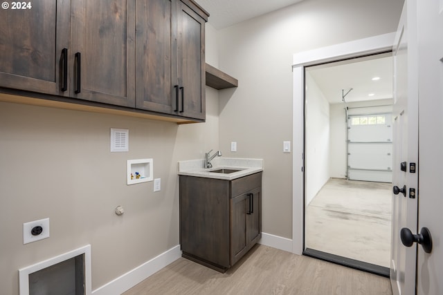 washroom featuring cabinets, sink, light hardwood / wood-style flooring, washer hookup, and hookup for an electric dryer