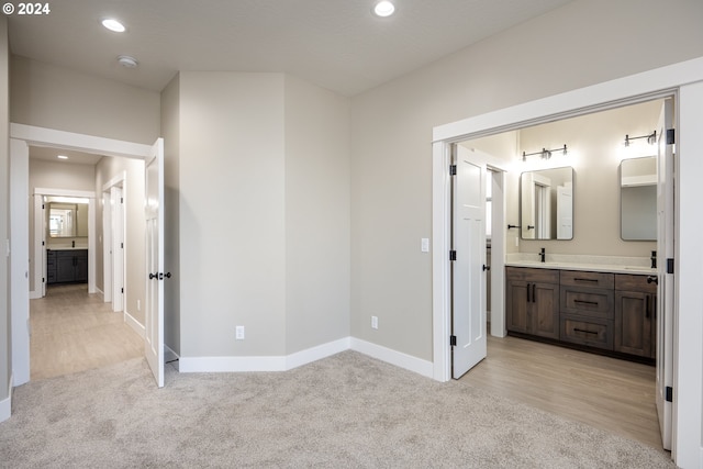 unfurnished bedroom featuring light colored carpet, ensuite bath, and sink