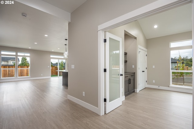 corridor with lofted ceiling and light wood-type flooring