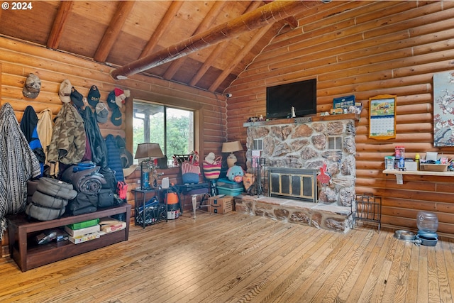 living room featuring log walls, wood-type flooring, high vaulted ceiling, wooden ceiling, and a stone fireplace