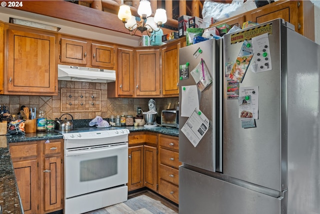 kitchen with tasteful backsplash, dark stone countertops, a chandelier, white electric range, and stainless steel refrigerator