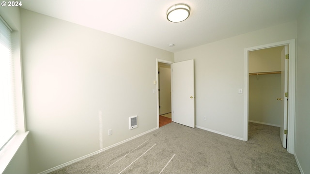 unfurnished bedroom featuring a closet, light colored carpet, and a walk in closet