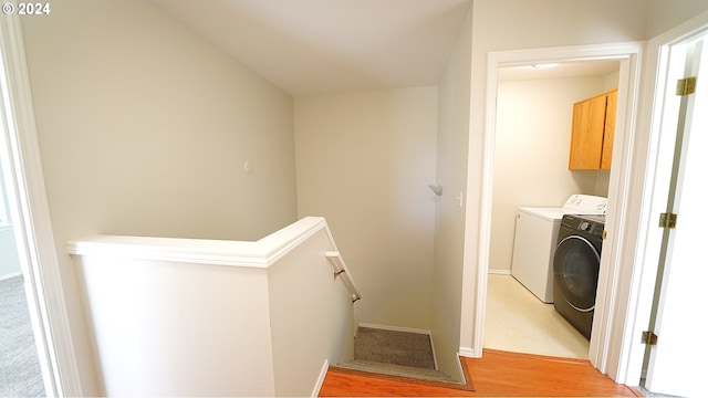 clothes washing area featuring cabinets, washer and dryer, and light wood-type flooring