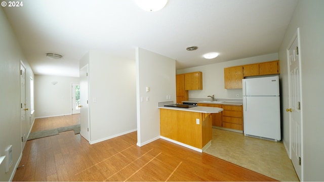 kitchen with sink, kitchen peninsula, light wood-type flooring, and white refrigerator