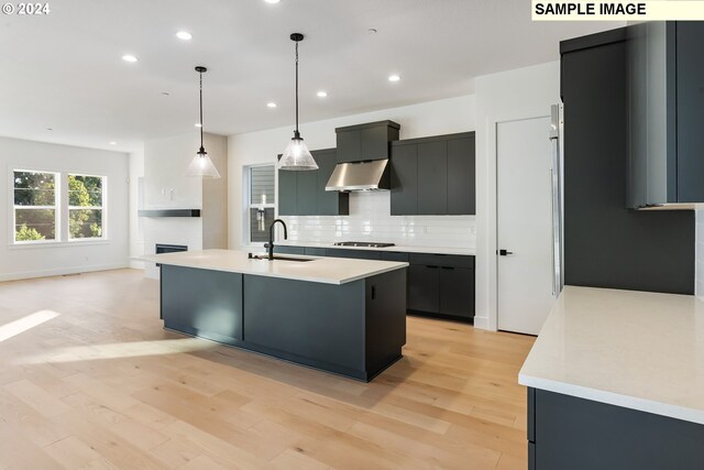 kitchen featuring pendant lighting, sink, range hood, an island with sink, and stainless steel gas stovetop