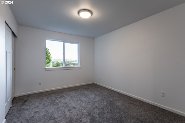 unfurnished room featuring dark colored carpet