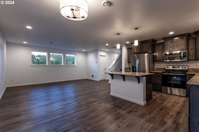 kitchen with pendant lighting, dark brown cabinets, appliances with stainless steel finishes, and a breakfast bar area