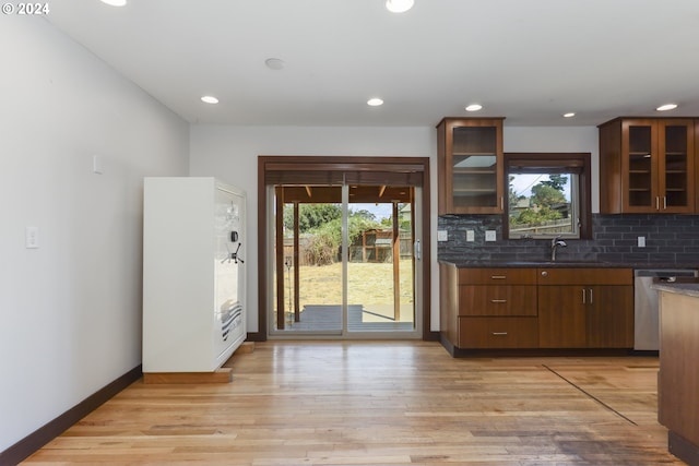 kitchen with dishwasher, sink, backsplash, and light hardwood / wood-style flooring