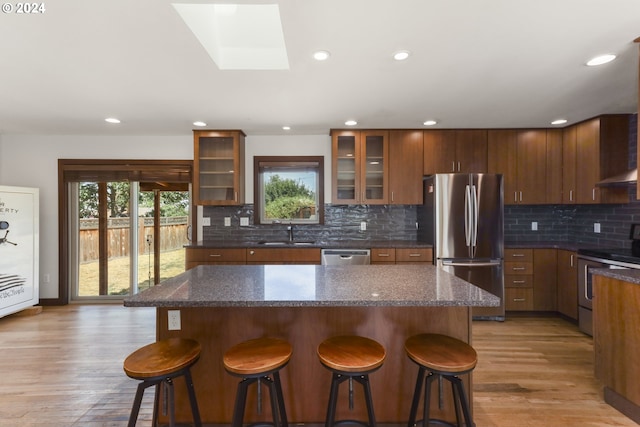 kitchen featuring backsplash, stainless steel appliances, a kitchen breakfast bar, light hardwood / wood-style floors, and a kitchen island