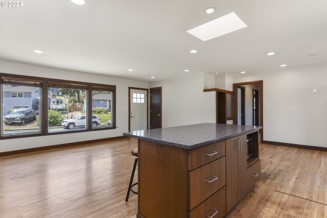 kitchen with a skylight, a center island, light hardwood / wood-style floors, and a breakfast bar area