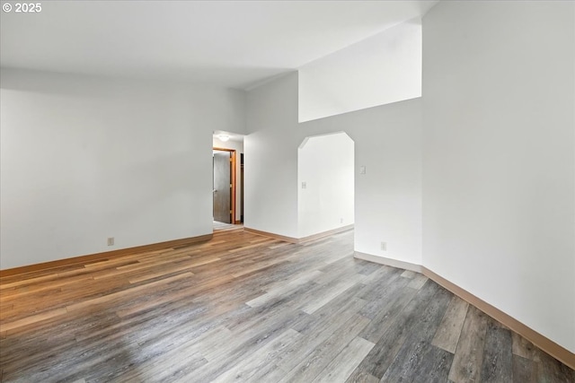 19875 SW Southview St, Beaverton, OR 97078 - spare room featuring arched walkways, wood finished floors, high vaulted ceiling, and baseboards