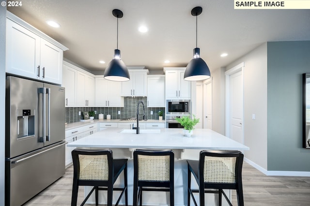 kitchen with white cabinets, decorative backsplash, stainless steel appliances, light countertops, and light wood-style floors