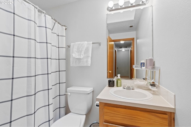 bathroom with walk in shower, vanity, and toilet