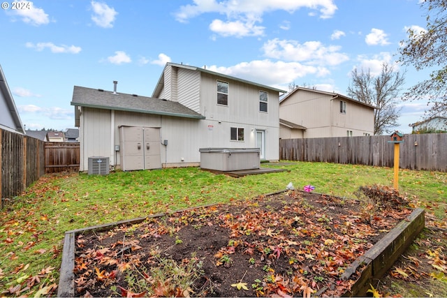 back of house featuring a yard, a hot tub, and central AC unit