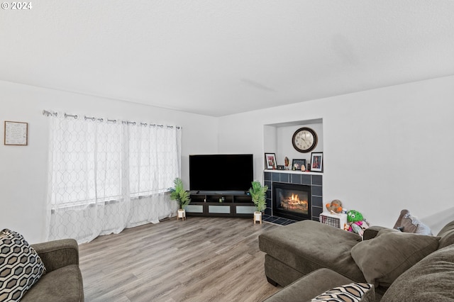 living room featuring light wood-type flooring and a tile fireplace