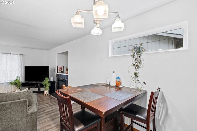 dining room featuring a tiled fireplace and hardwood / wood-style flooring