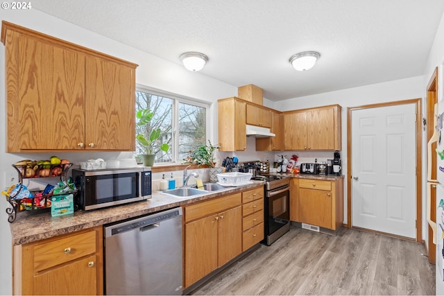 1108 SW Ivory Loop, Gresham, OR 97080 - kitchen featuring stainless steel appliances, under cabinet range hood, light wood-style floors, and a textured ceiling