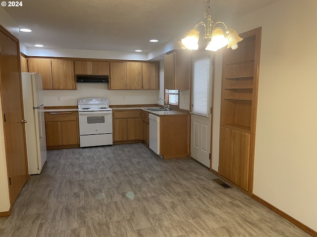 kitchen with white appliances, an inviting chandelier, sink, hanging light fixtures, and range hood