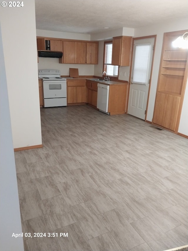 kitchen featuring white appliances, ventilation hood, and sink