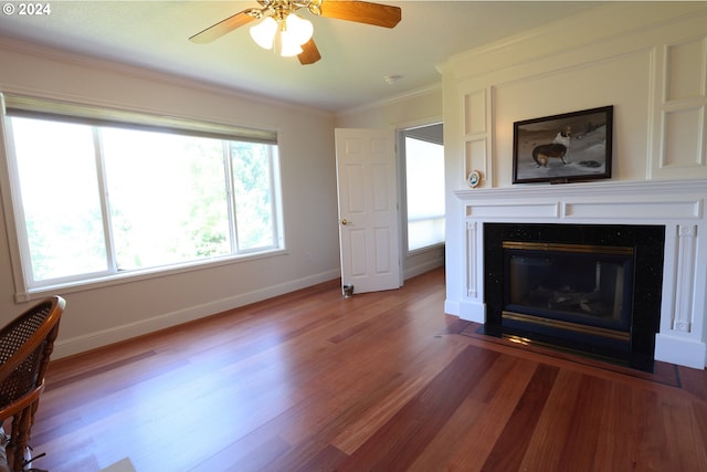 unfurnished living room featuring a wealth of natural light, ceiling fan, wood-type flooring, and ornamental molding