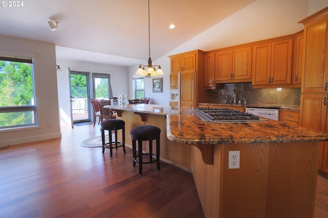 kitchen featuring vaulted ceiling, a spacious island, decorative light fixtures, a notable chandelier, and a breakfast bar area