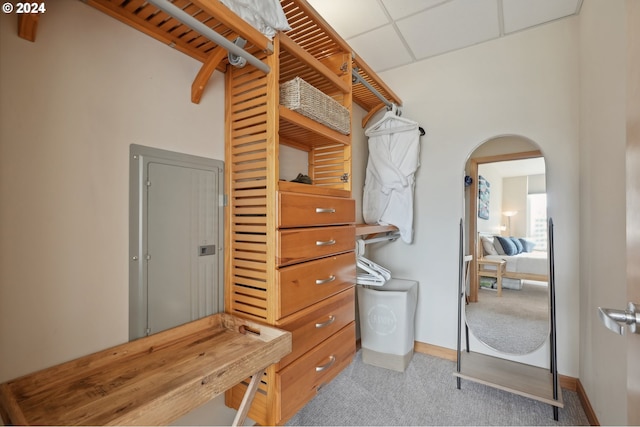 spacious closet with light carpet, arched walkways, and a drop ceiling