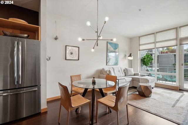 dining room featuring dark wood-type flooring, a chandelier, baseboards, and a wall of windows