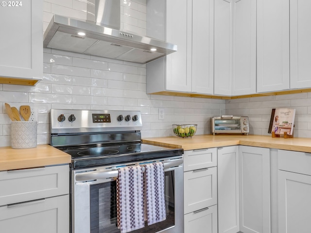 kitchen featuring stainless steel electric range, white cabinetry, wood counters, and wall chimney exhaust hood