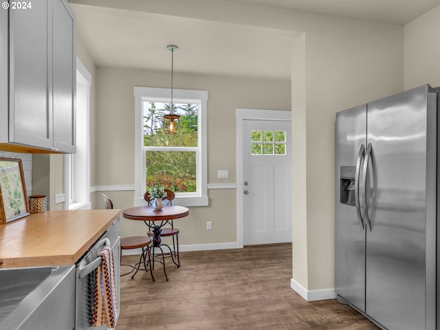 kitchen featuring stainless steel appliances, wood-type flooring, and decorative light fixtures