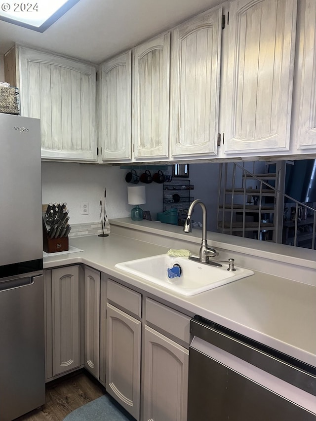 kitchen featuring appliances with stainless steel finishes, sink, and dark wood-type flooring