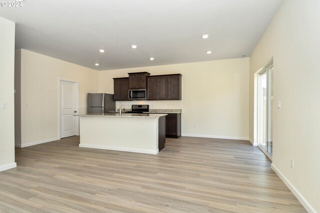 kitchen featuring a kitchen island with sink, light wood-style flooring, recessed lighting, stainless steel appliances, and dark brown cabinets