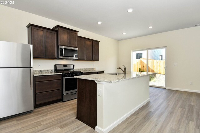 kitchen with recessed lighting, a kitchen island with sink, dark brown cabinetry, appliances with stainless steel finishes, and light wood-type flooring