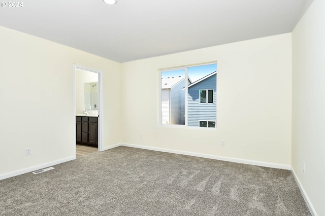 empty room featuring visible vents, baseboards, and light carpet