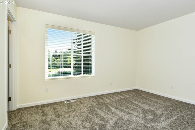 empty room with baseboards, visible vents, and carpet floors