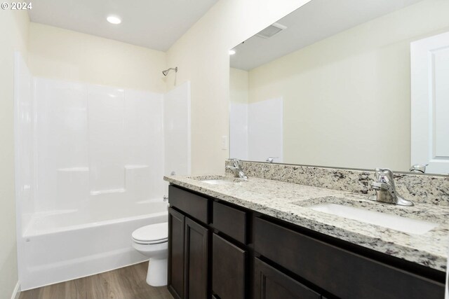 full bath featuring a sink, toilet, tub / shower combination, and wood finished floors