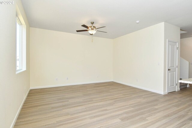 spare room featuring a ceiling fan, baseboards, light wood-type flooring, and a wealth of natural light