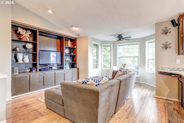 living room with ceiling fan, light hardwood / wood-style floors, and vaulted ceiling