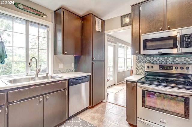 kitchen featuring backsplash, dark brown cabinetry, stainless steel appliances, sink, and light tile patterned floors