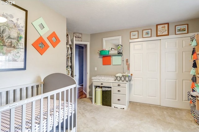 carpeted bedroom with a closet and a nursery area