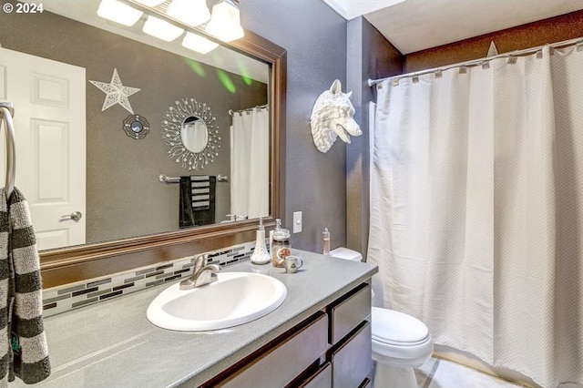 bathroom with vanity, toilet, and tasteful backsplash