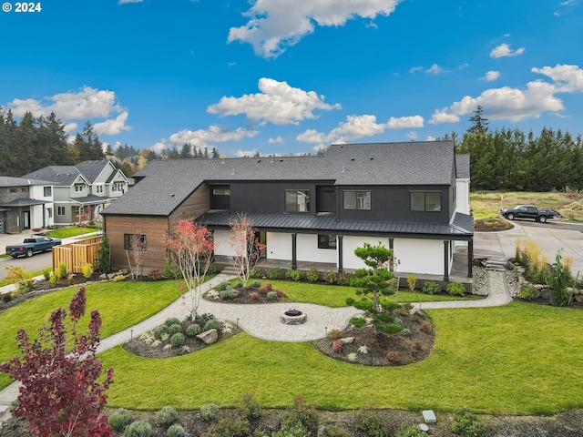 view of front of property featuring metal roof, roof with shingles, a front lawn, and fence