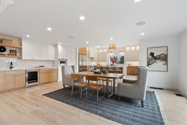 dining area with wine cooler, recessed lighting, and light wood-style flooring