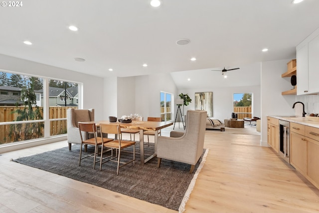 dining space with light hardwood / wood-style floors, sink, ceiling fan, beverage cooler, and lofted ceiling