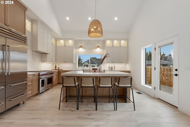 kitchen with visible vents, light countertops, decorative backsplash, light wood-style floors, and high end appliances