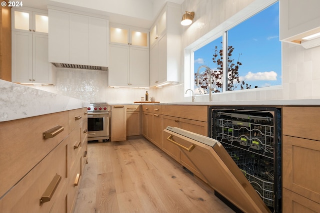 kitchen featuring backsplash, beverage cooler, premium stove, light countertops, and light wood-type flooring