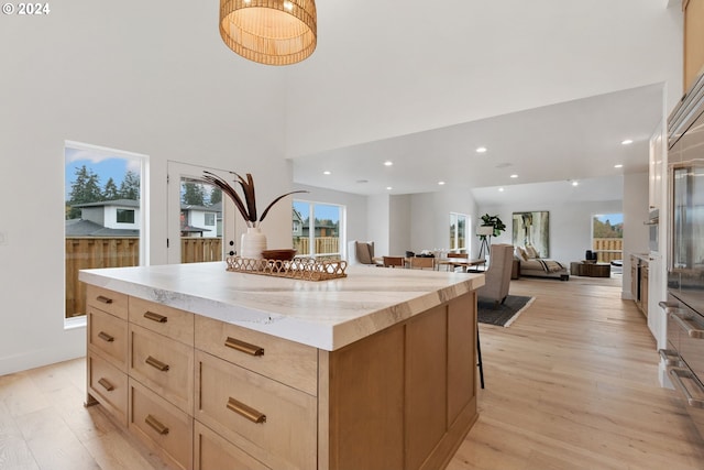 23141 SW Curry Ridge Dr, Sherwood, OR 97140 - kitchen with light wood-type flooring, a kitchen bar, a kitchen island, recessed lighting, and open floor plan